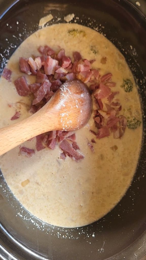 adding in the chopped ham to the ham and broccoli crockpot soup.