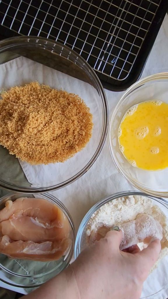 Dipping chicken tender in flour.