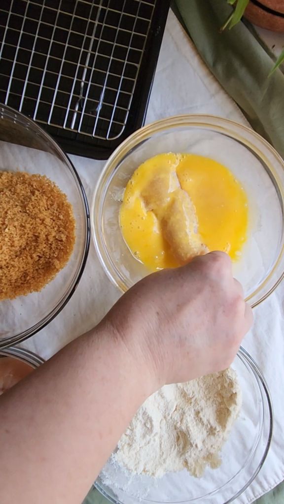 Dipping chicken tender in egg wash