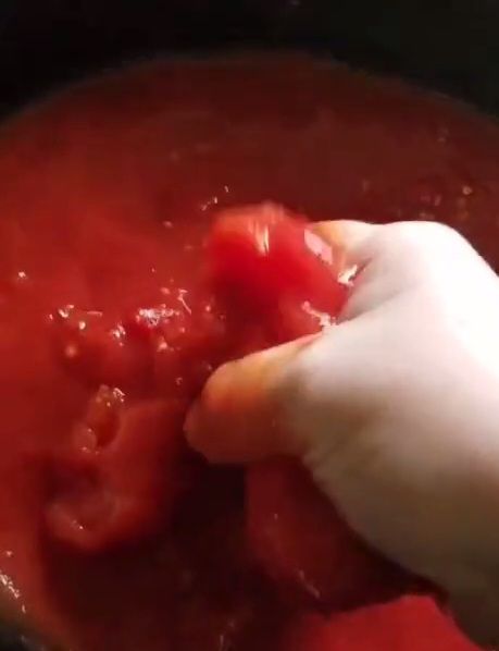 Smashing hole stewed tomatoes with my hands for quick and easy keto marinara sauce recipe.