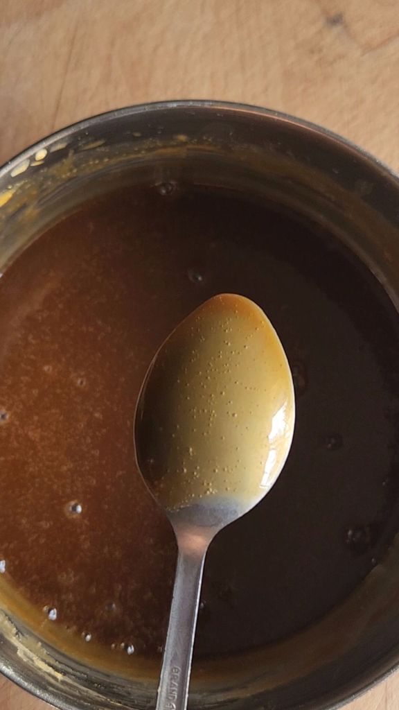 Checking the thickness of the easy homemade low carb butterscotch syrup recipe after simmering.
