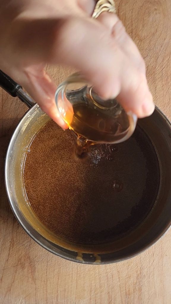 pouring the vanilla extract into the easy homemade low carb butterscotch syrup.