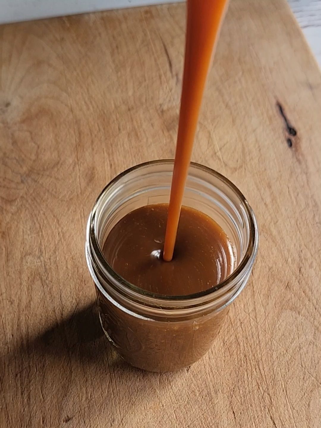 Pouring easy homemade low carb butterscotch syrup in a jar.