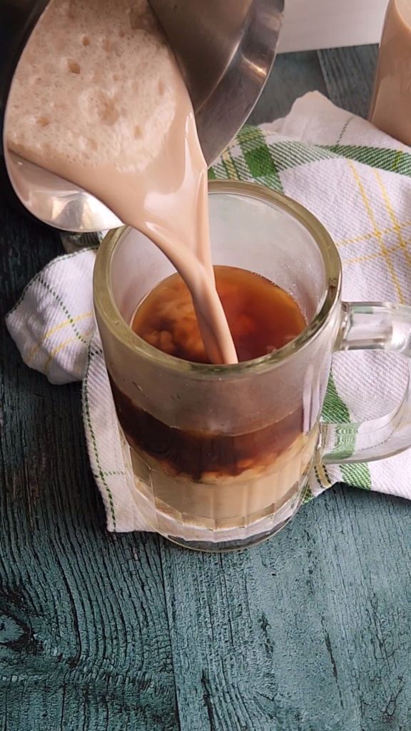 Pouring the best low carb copycat babies Irish cream into a coffee drink.