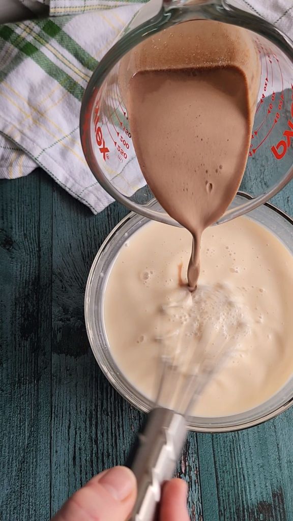 Pouring low carb copycat Bailey's Irish Cream into unsweetened almond milk.