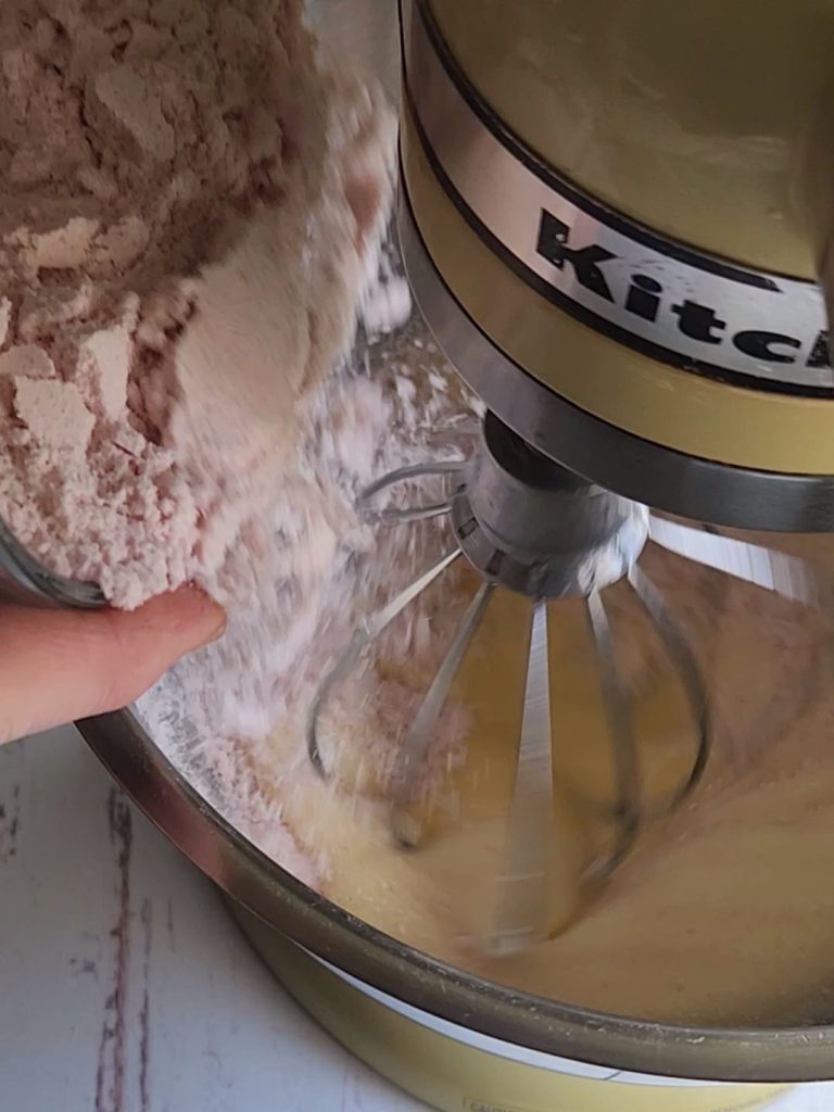 Pouring the dry ingredients into the mixing bowl making the best gluten-free strawberry pudding cake recipe.