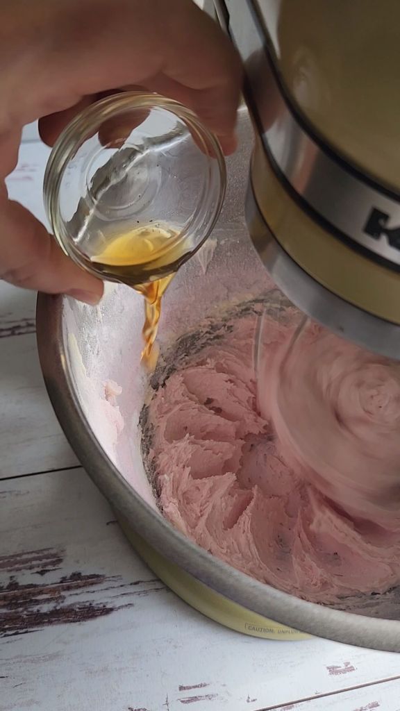 Pouring vanilla extract into the sugar-free strawberry frosting recipe.