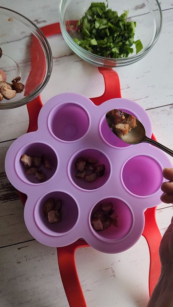 Portioning sausage pieces into the wells of the egg bite mold.