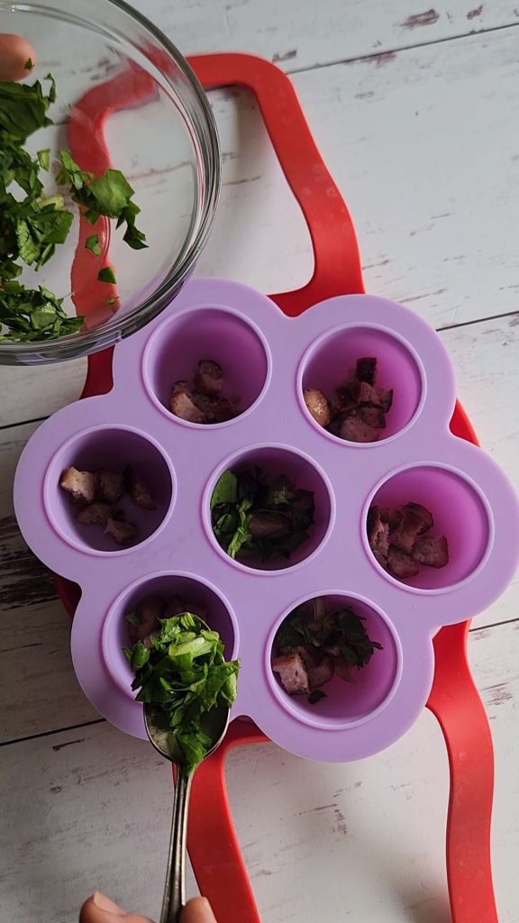 Putting spinach into the wells of the silicone egg bite mold.