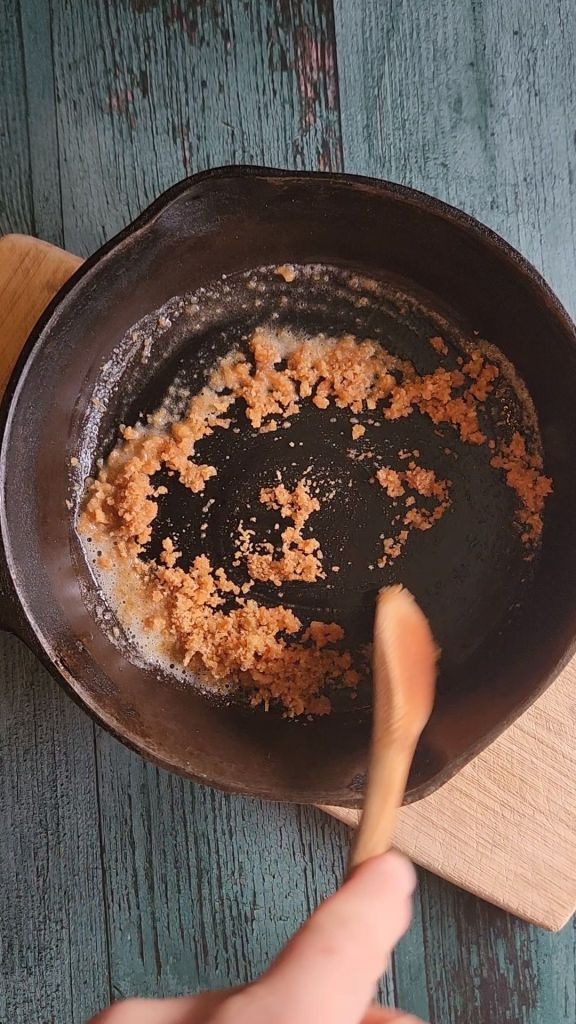 Mixing pork rind topping with melted butter for Easy gluten-free chicken Divan casserole.