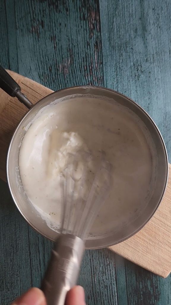 Whisking cream cheese into cream soup in saucepan for Easy gluten-free chicken Divan casserole recipe.