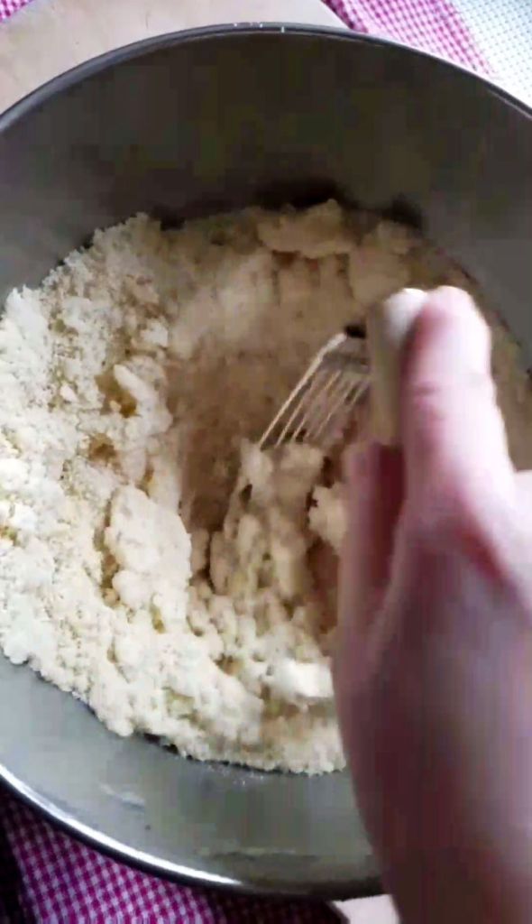 Cutting the butter into the almond flour for the crust of gluten-free strawberry rhubarb crumble bars.