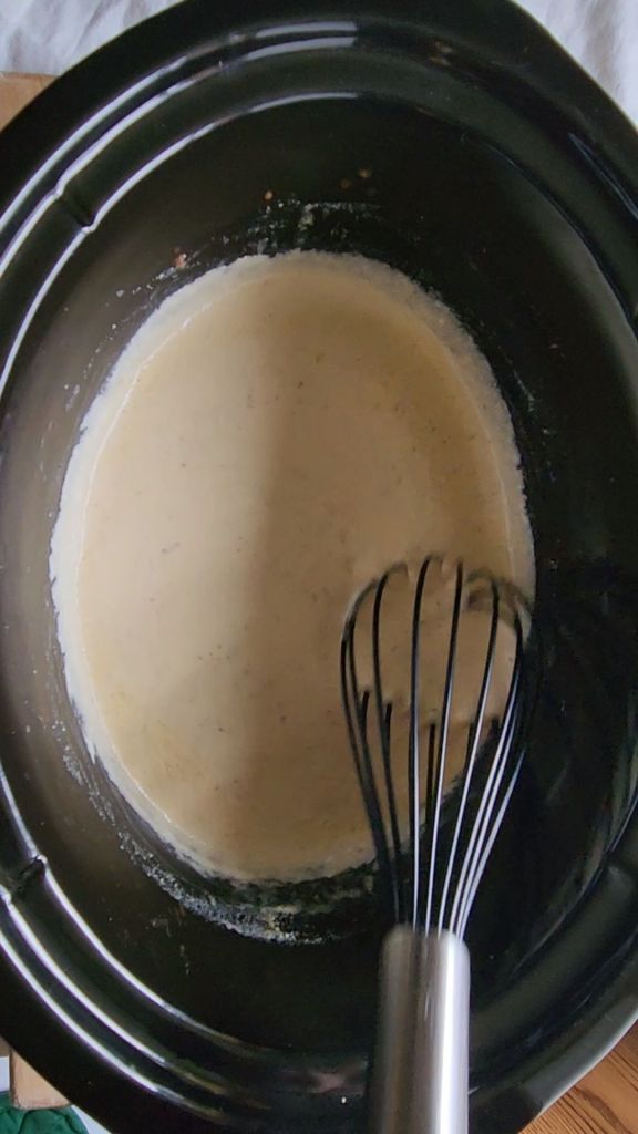 Final stirring of easy gluten-free crock pot Ragu alfredo sauce in crock-pot.