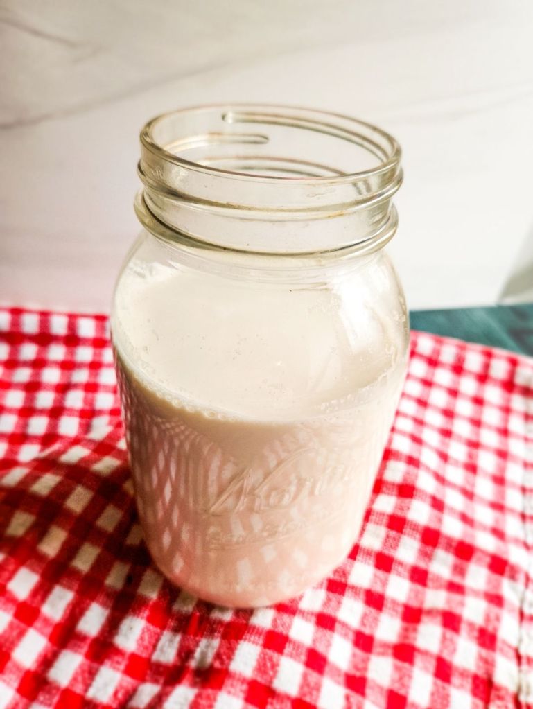 Strained almond milk in a glass quart jar.