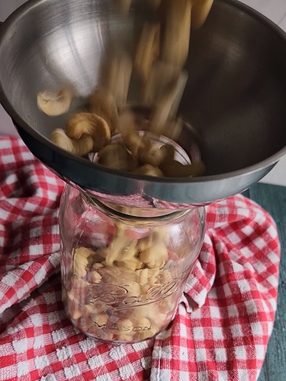 Measuring raw cashews into a quart jar for soaking overnight.