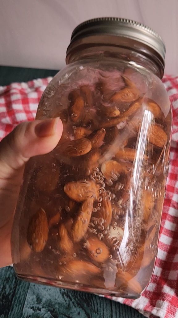 Quart jar filled with raw almonds and water for soaking overnight.