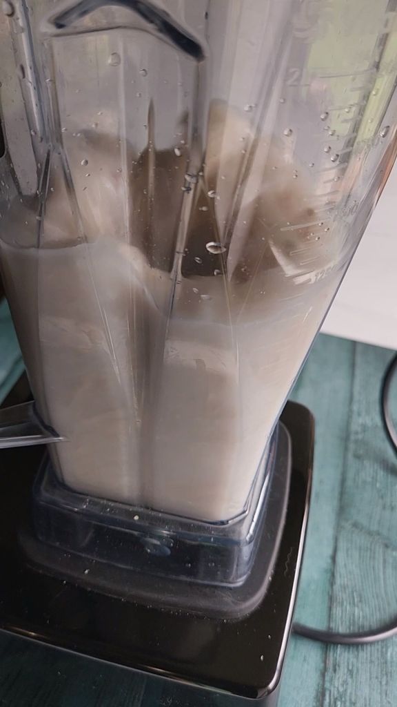 Blending soaked raw cashews with water in a Vitamix blender.