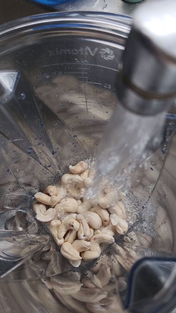 Pouring water in blender was soaked cashews.