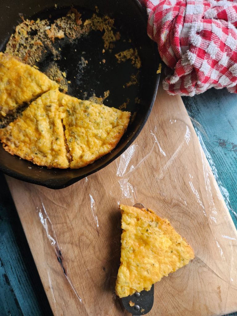 Wrapping up triangle pieces of sausage and cheese frittata in plastic wrap for freezing.