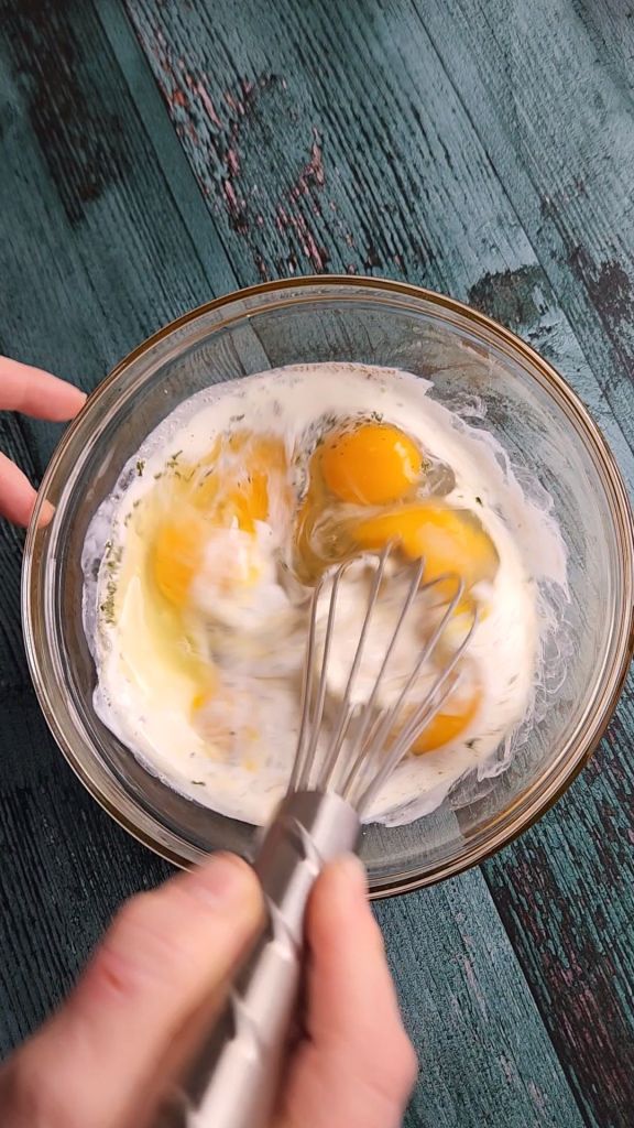 Wrapping up triangle pieces of sausage and cheese frittata in plastic wrap for freezing.