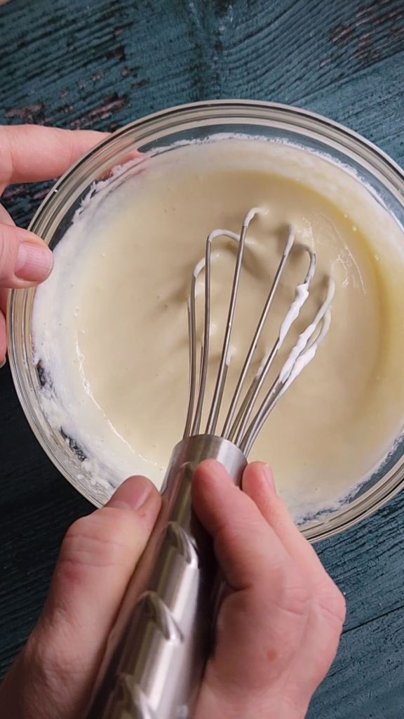 Egg mixture for Grandma's gluten-free cinnamon coffee cake recipe being whisked in a bowl.