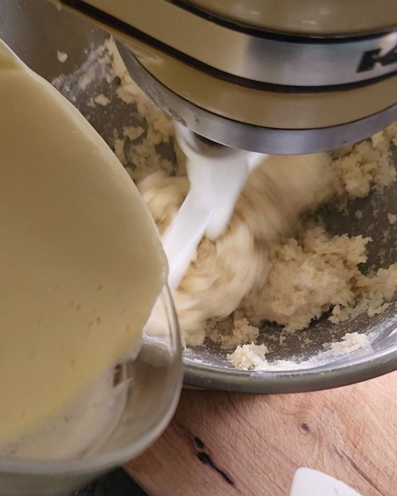 Pouring egg mixture into main cake batter for Grandma's gluten free cinnamon coffee cake recipe.