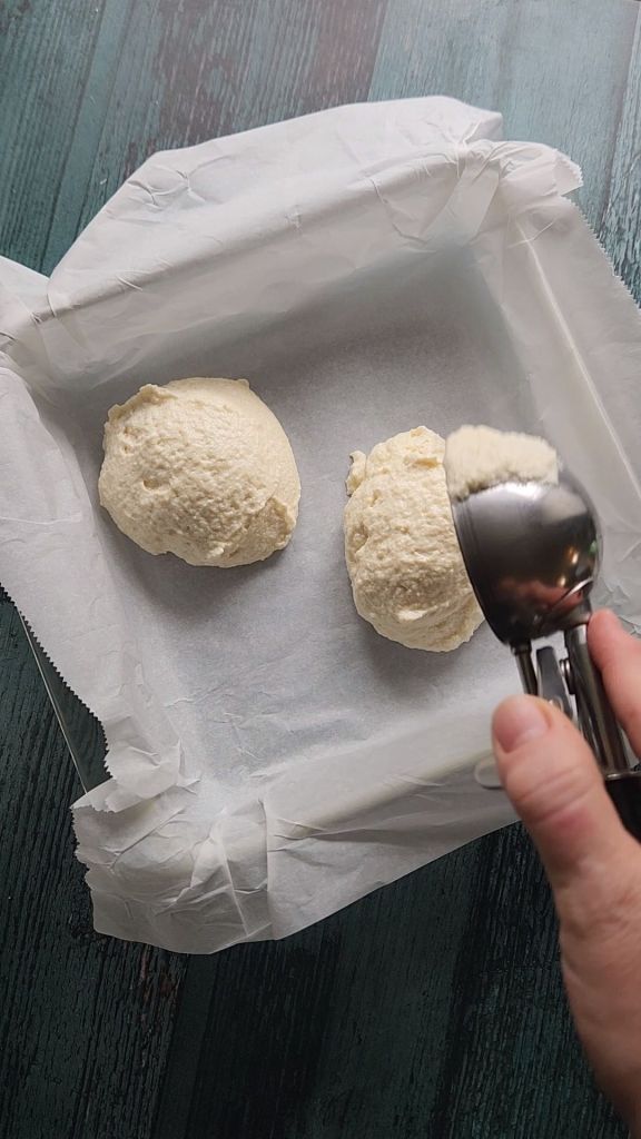 Scooping first layer of cake batter into pan for Grandma's gluten-free cinnamon coffee cake recipe.