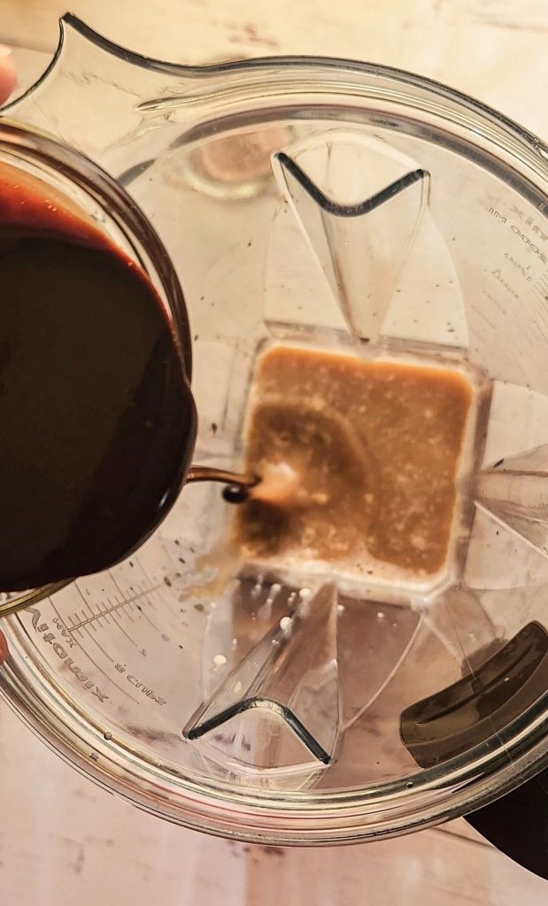 Pouring sugar-free chocolate syrup into the blender to make low carb copycat Starbucks caramel mocha frappuccino.