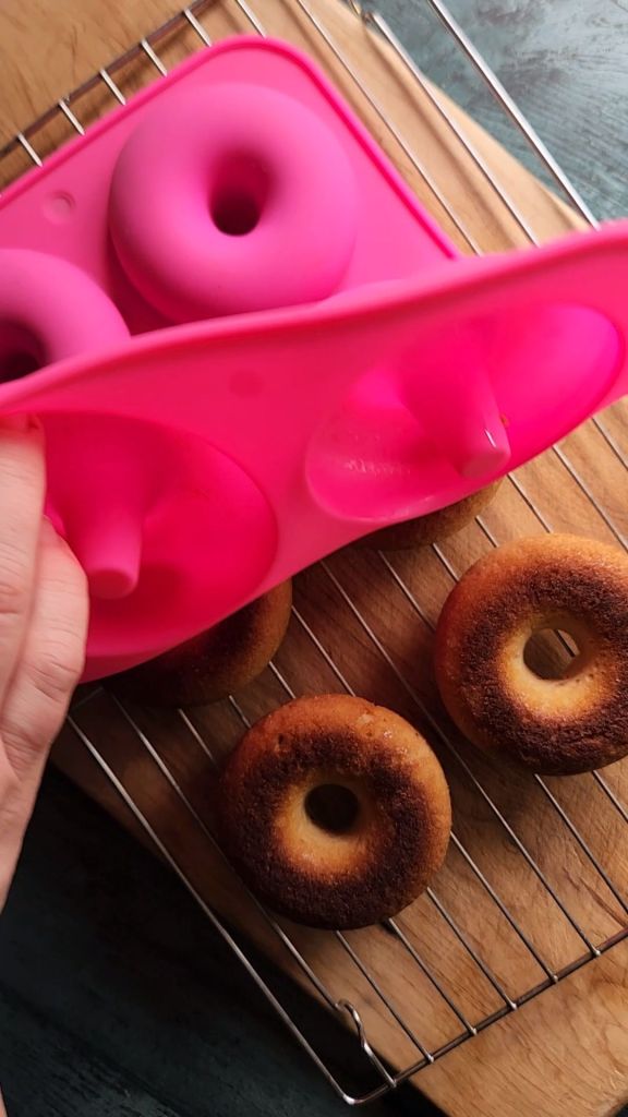 Peeling silicone donut pan off of baked gluten-free maple donuts.