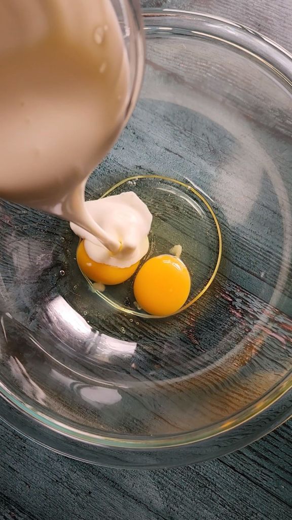 Adding heavy cream to eggs in bowl.