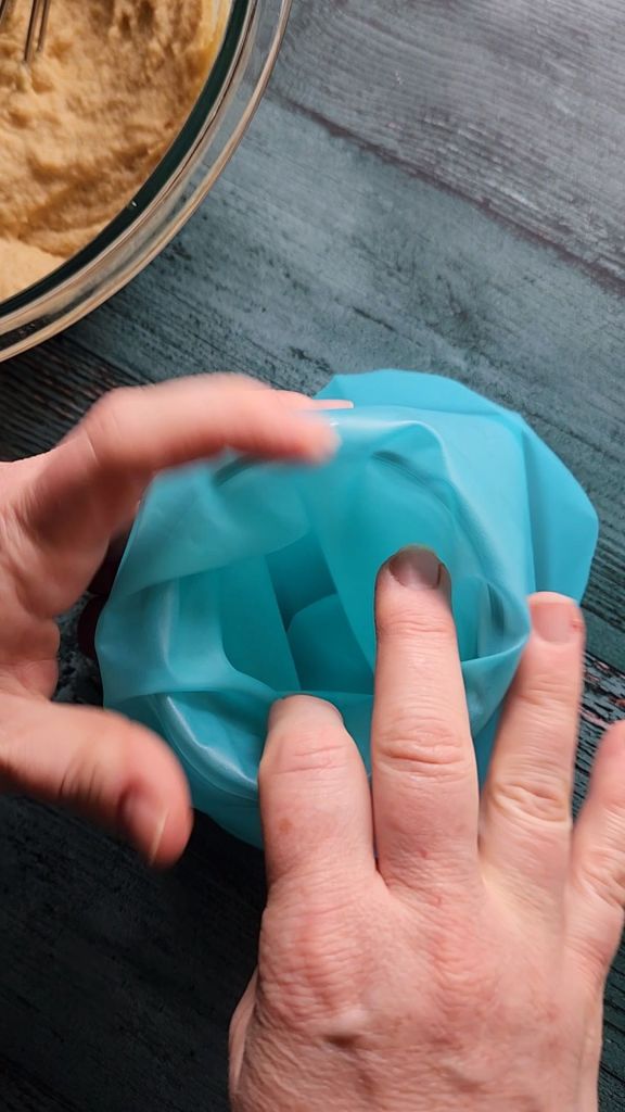 Pulling sides of piping bag down around wide mouth jar for stabilization.