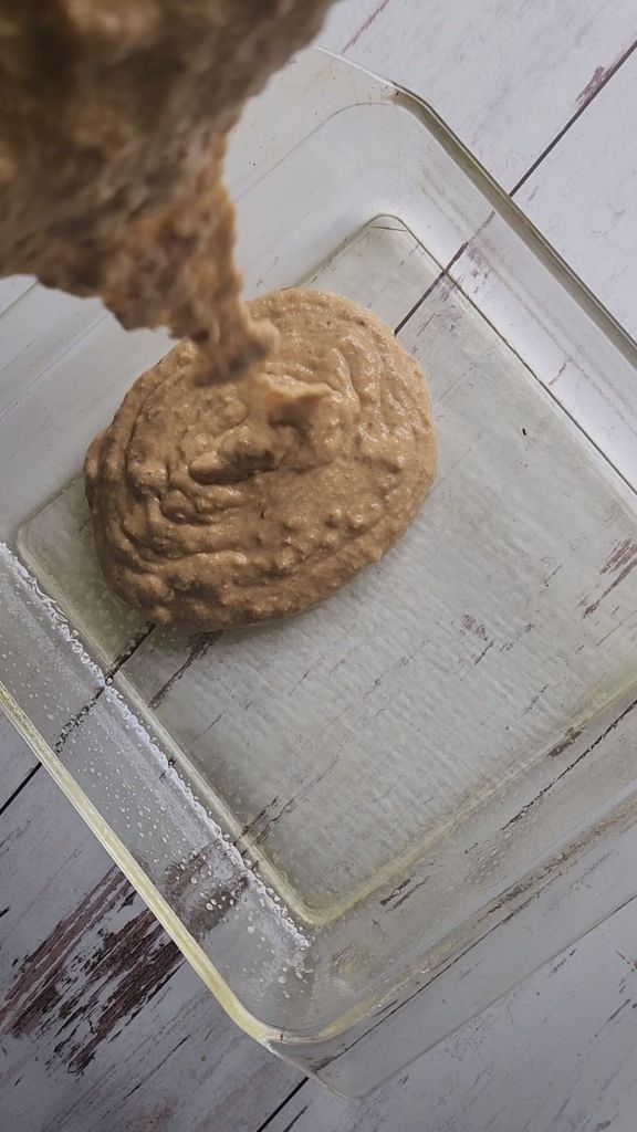 Pouring better for easy gluten-free fluffy baked pecan pancake into an 8x8 pan.