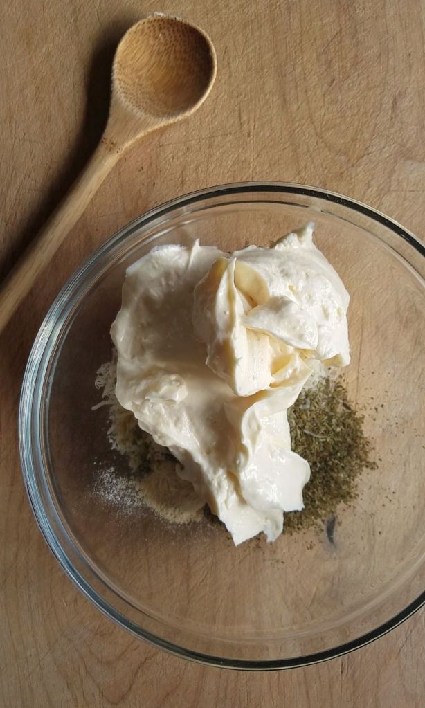 Adding all ingredients for parmesan mixture to make gluten-free creamy Italian parmesan chicken dinner.