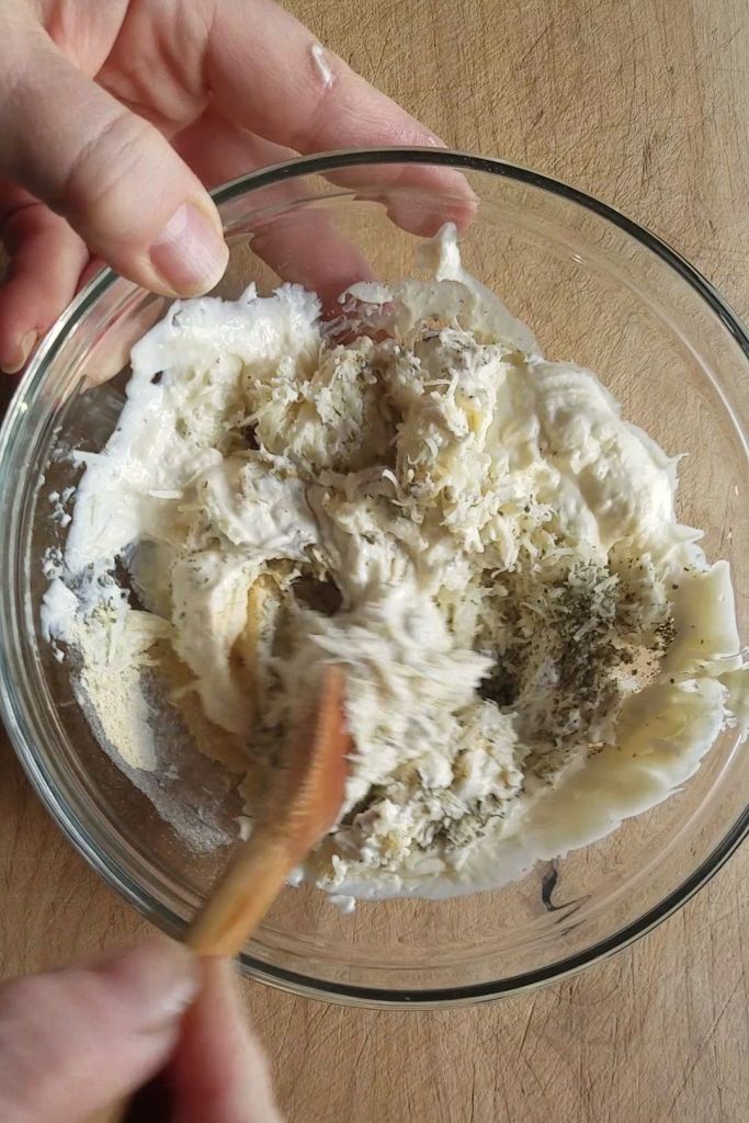 Mixing ingredients for gluten-free creamy Italian parmesan chicken dinner topping.