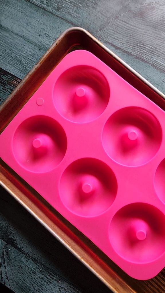 Silicone donut pan on a baking sheet for stability.