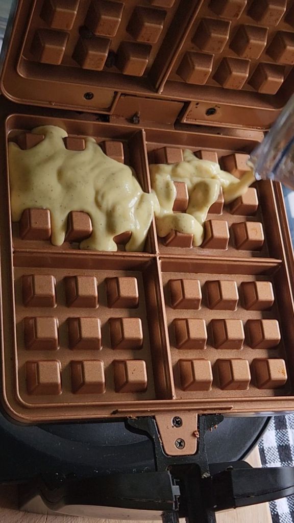 Batter for easy gluten-free keto mini pizza chaffles recipe being added to the waffle maker.