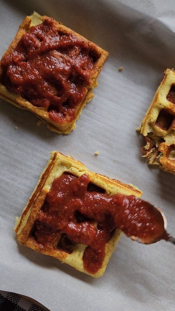Adding keto marinara sauce to gluten-free keto mini pizza chaffles crusts.