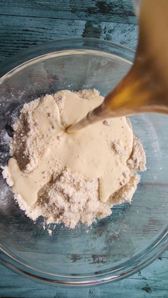 Adding wet ingredients to dry ingredients to make gluten-free scones.