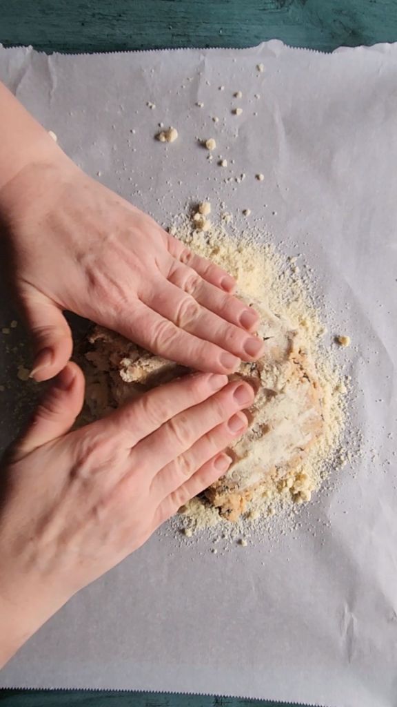 Patting out scone dough onto parchment lined baking sheet.
