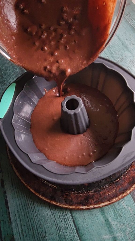 Pouring batter for gluten-free Bailey's Irish cream chocolate bundt cake into the greased bundt cake pan.