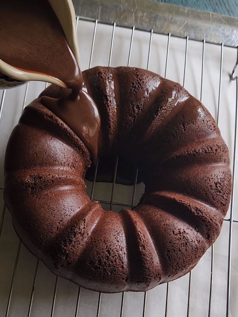 Gluten free Baileys Irish Cream chocolate bundt cake being covered with sugar-free chocolate glaze.