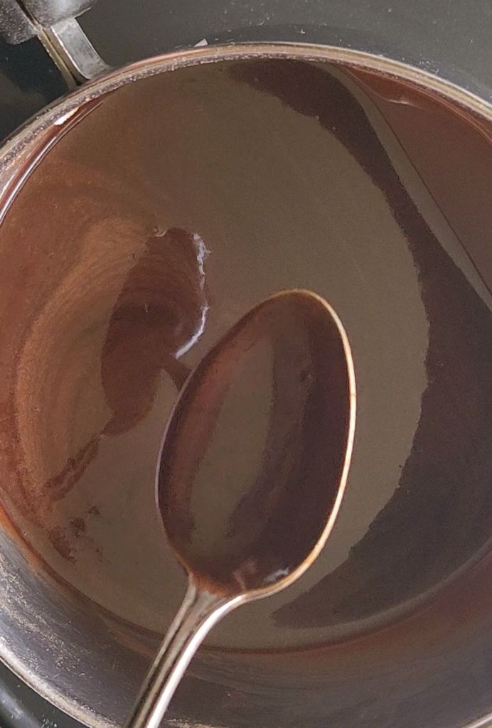 Checking the sugar-free chocolate glaze to see if it'll coat a spoon.