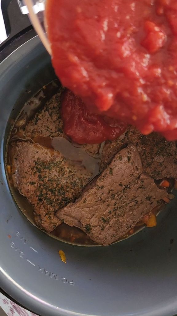 Pouring tomato sauce mixture over seared round steaks in instant pot for easy gluten-free copycat McCormick Swiss steak recipe.