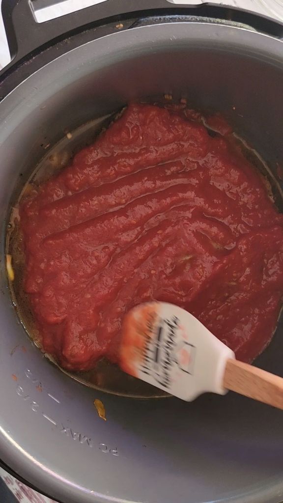 Spreading tomato mixture evenly over seared round steaks in instant pot for easy gluten-free copycat McCormick Swiss steak recipe.