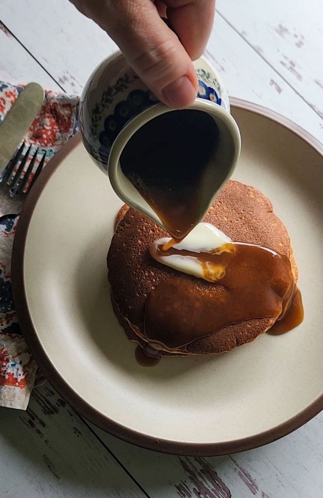 Pouring keto maple syrup over easy gluten free blender pancakes.