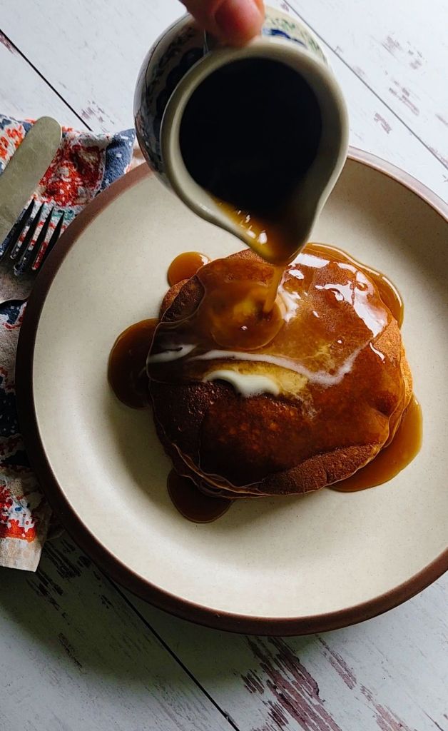 Pouring keto maple syrup over easy gluten free blender pancakes.