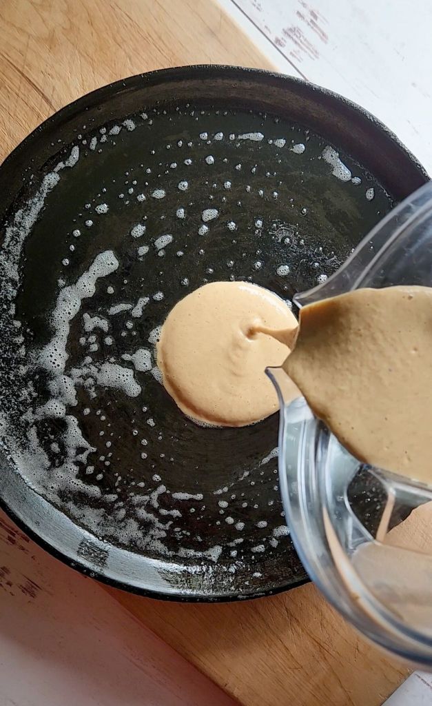 Pouring batter for easy gluten.Free blender pancakes onto prepared skillet.