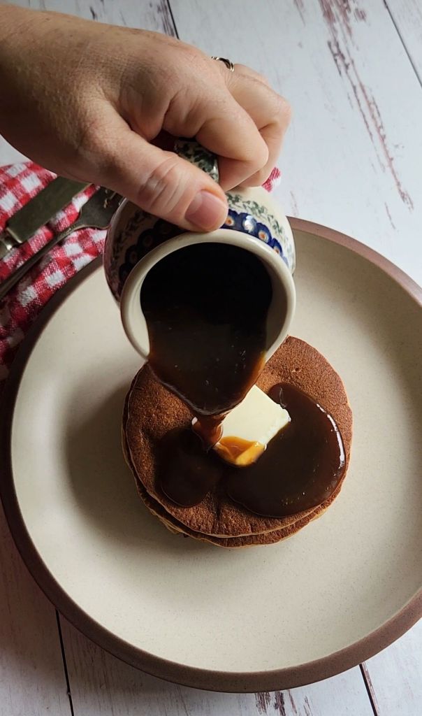 Pouring keto maple syrup over easy gluten free blender pancakes.
