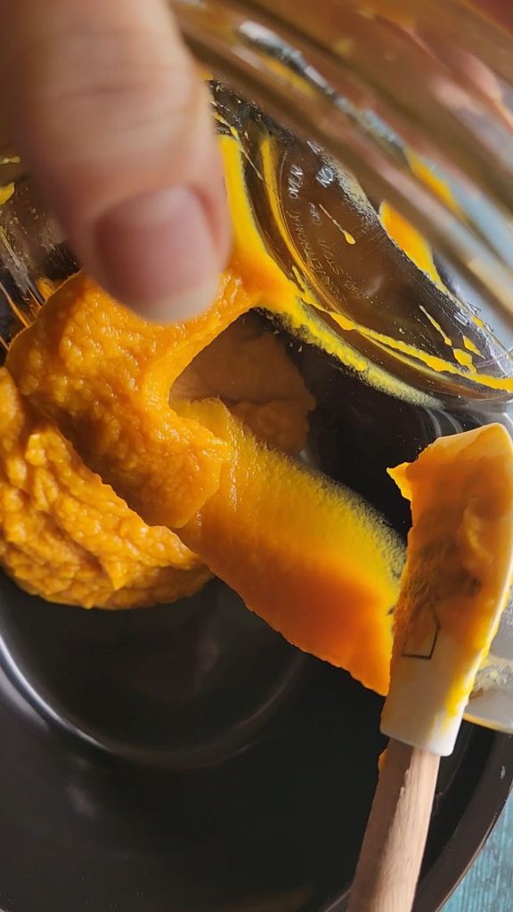 Scraping pumpkin puree into the crock pot for Easy crock pot sugar free pumpkin butter recipe.