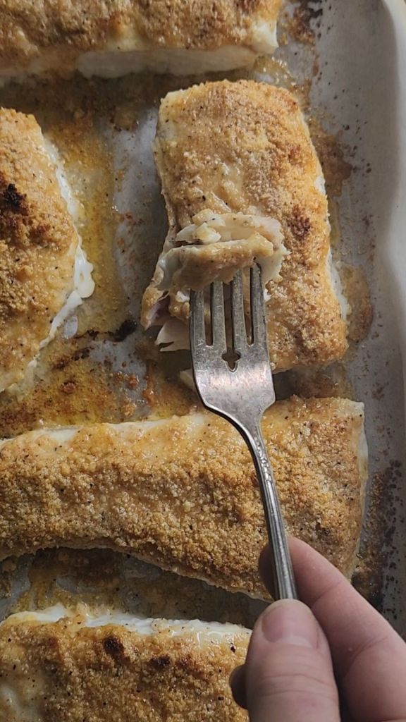 Flaking off a piece of baked gluten free almond crusted lemon garlic halibut.